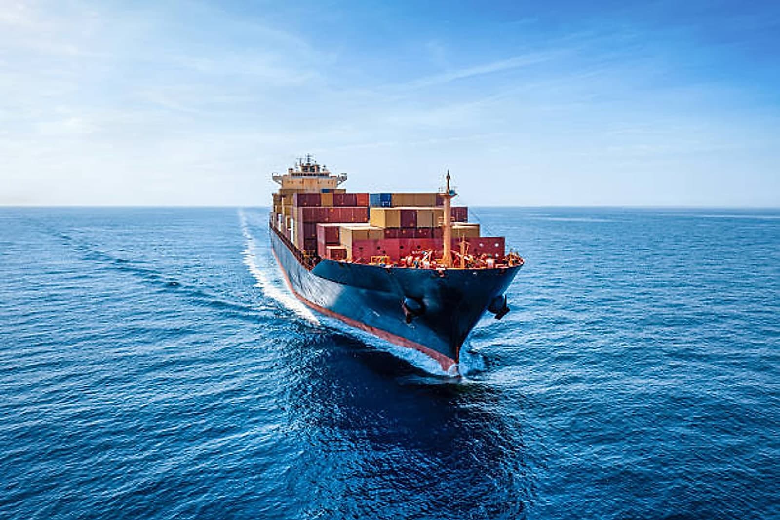 A container ship loaded with export containers sailing across open sea